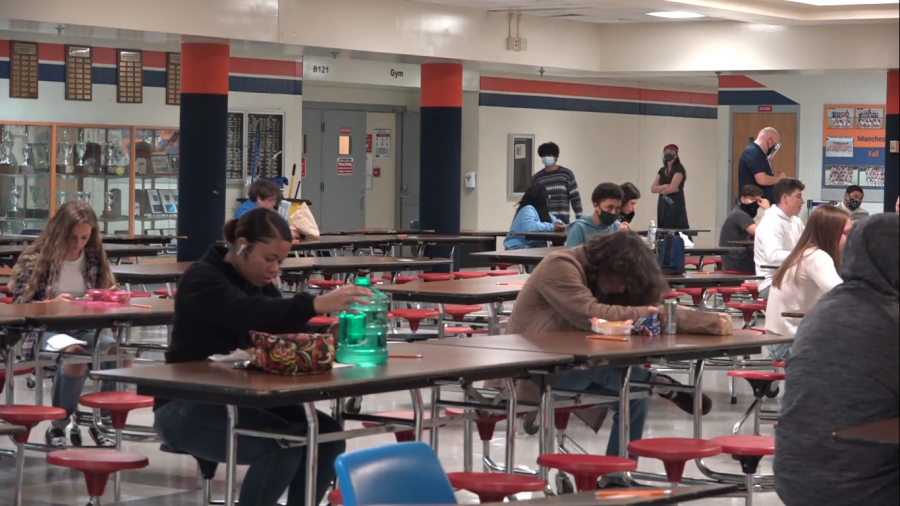 Students eating lunch in the cafeteria. They are socially distanced and sitting far apart from each other.