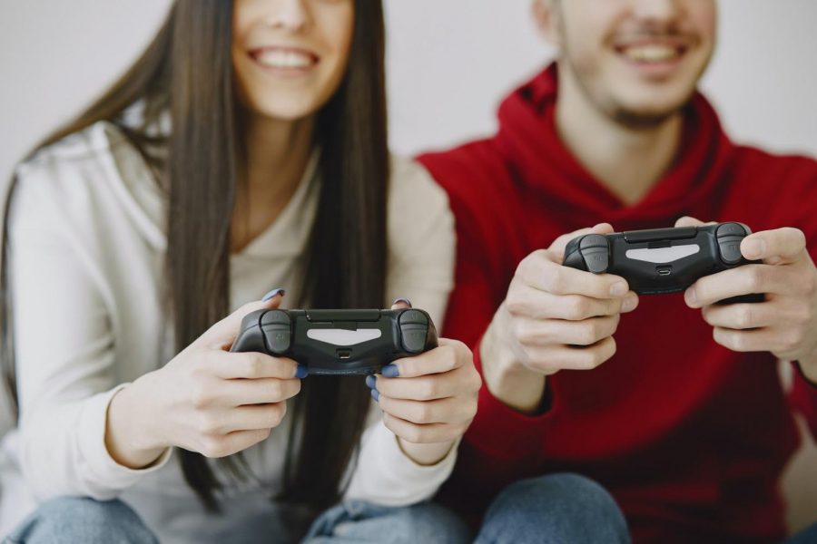 Two people play video games on a couch