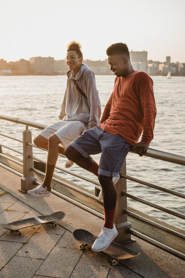 Two young men sitting on the railing of a pier