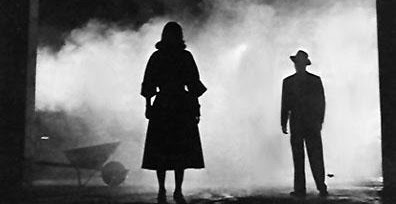 Two silhouetted figures standing in fog